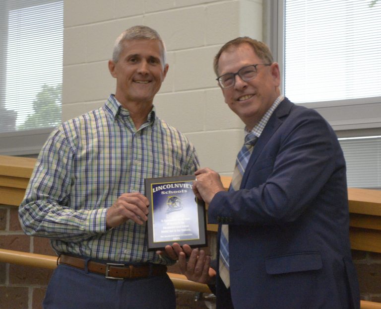 Lincolnview Athletic Director Greg Leeth received a plaque from Superintendent Jeffrey Snyder. Leeth and his wife Brenda, a school counselor, are retiring from the school district. (Sam Shriver/CherryRoad Media)