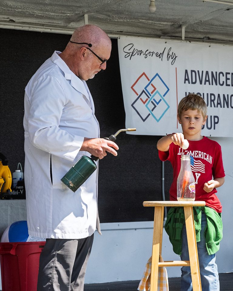 Dr. Dave Lohnes and an assistant demonstrate how an egg can be sucked into a bottle. (Bob Barnes for the Times Bulletin)